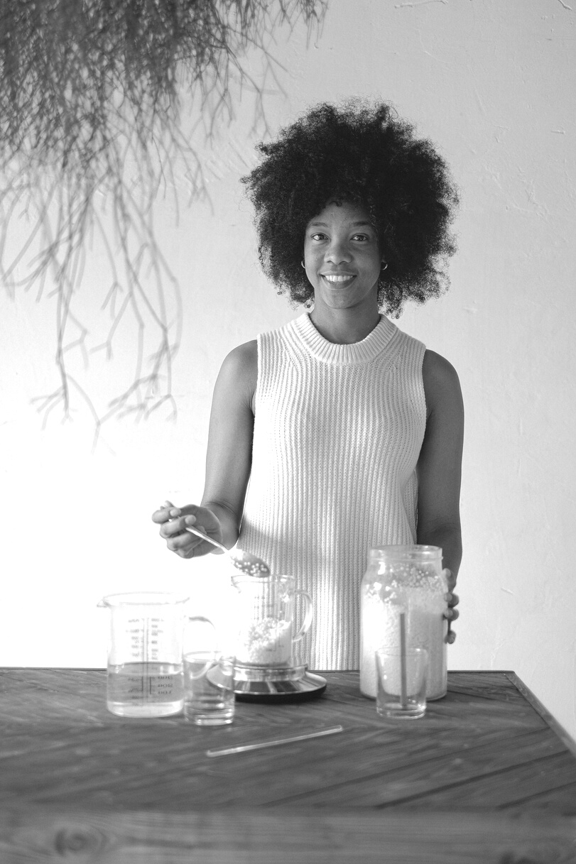 Cheerful black woman with wax pellets making candles
